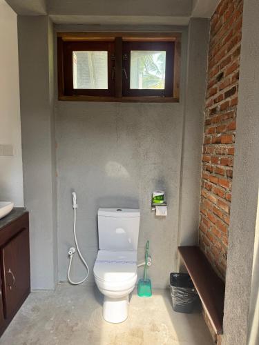 a bathroom with a white toilet in a brick wall at Steps Garden Resort in Negombo