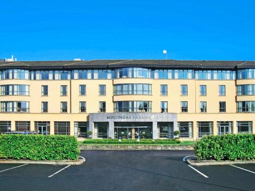 a large building with a parking lot in front of it at Family Friendly Mullingar Self Catering Apartment on Park Hotel Grounds in Mullingar