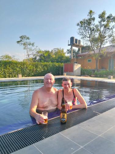 a man and woman sitting in a swimming pool with beer at Tiara Elephant Lodge in Habarana