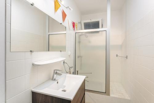 une salle de bain blanche avec un lavabo et une douche dans l'établissement Maison Bordure de Forêt et vue Mer, à Saint-Trojan-les-Bains