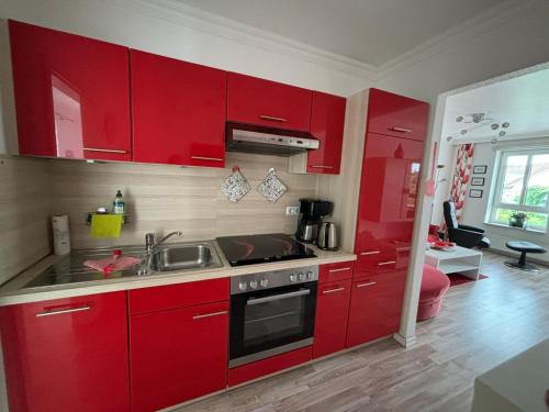 a kitchen with red cabinets and a sink at " Stadtwohnung Ausspann " in Heiligenhafen