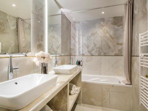 La salle de bains blanche est pourvue d'un lavabo et d'une baignoire. dans l'établissement Merveil Luxury Suite - Martin VII - Museum view, à Paris