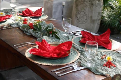 a wooden table with red napkins and plates on it at Marni alas villa ubud in Tegalalang