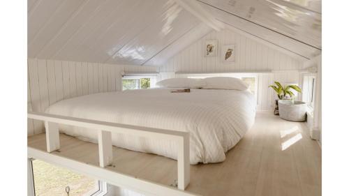 una camera da letto con letto bianco in mansarda di Kookaburra Tiny House by Tiny Away a Palmwoods