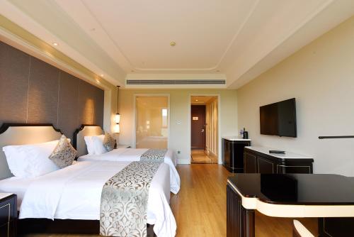 a hotel room with two beds and a flat screen tv at Ramada Plaza by Wyndham Wenzhou in Wenzhou