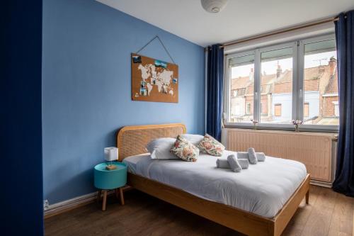 une chambre avec un lit avec un mur bleu dans l'établissement Family Home in Lille, Garden and Parking - 6/8p, à Lille