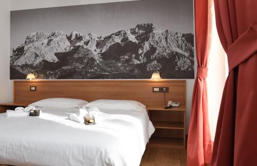a bedroom with a large white bed with mountains on the wall at Park Residence Imperator in Carisolo