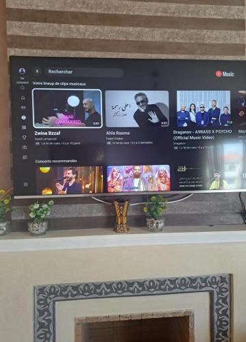 a tv over a fireplace with a screen above it at Garden Beach 2 sidi rahal in Sidi Rahal