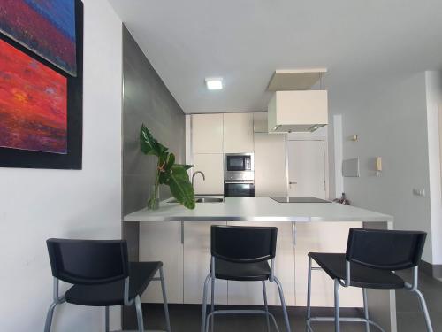 una cucina con tre sedie e un bancone da cucina di Apartamento Sunset Terraza a Puerto Naos