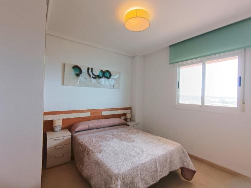un dormitorio con una cama y una ventana en Ayf vistas de lujo en 1ª linea de playa, en El Borseral