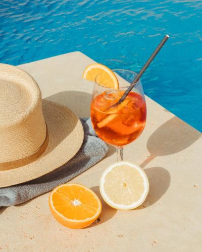 a drink with a straw and a hat next to a pool at Ogygia Suites Gozo in Għarb