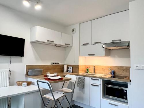 une cuisine avec des armoires blanches et une table et des chaises dans l'établissement Studio équipé avec Balcon et Accès rapide à Lille, à Croix