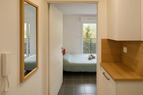 un couloir menant à une chambre avec un lit et un miroir dans l'établissement Studio équipé avec Balcon et Accès rapide à Lille, à Croix