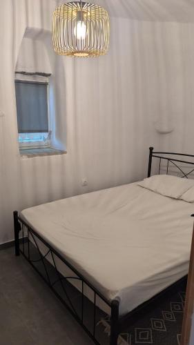 a bed in a room with a window and a chandelier at Katoi Apartment in Loutrá