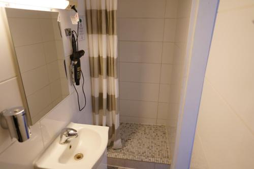 a bathroom with a sink and a shower with a mirror at Hotel Xantener Eck in Berlin