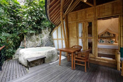 a wooden deck with a bath tub and a table and chair at Marni alas villa ubud in Tegalalang