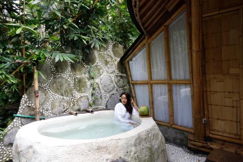 a woman sitting in a large bath tub at Marni alas villa ubud in Tegalalang