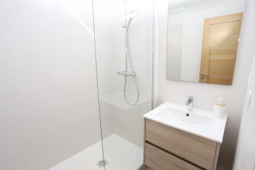 une salle de bain blanche avec une douche et un lavabo dans l'établissement Duplex face mer avec solarium et piscine, à Saint-Cyprien