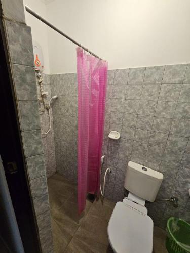 a bathroom with a toilet and a pink shower curtain at Latheena Resort in Weligama