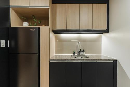 eine Küche mit einem schwarzen Kühlschrank und einer Spüle in der Unterkunft Muji Home Staycation in Eastwood Global Plaza in Manila