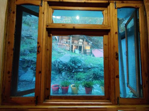 a window with potted plants in a room at Flipsyde Retreat in Kasol