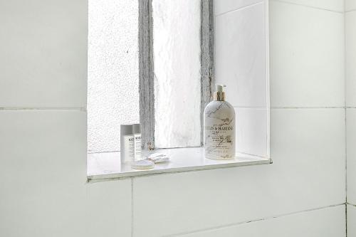 une bouteille d'alcool posée sur le rebord d'une fenêtre dans une salle de bain dans l'établissement Nid douillet pour deux dans le Paris des artistes, à Paris