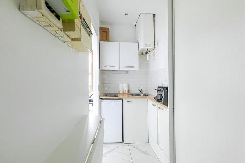 une cuisine blanche avec des armoires et des appareils blancs dans l'établissement Nid douillet pour deux dans le Paris des artistes, à Paris