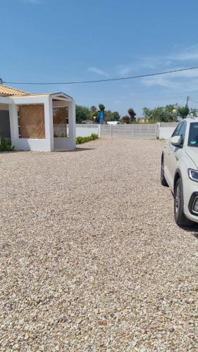 a car parked in a gravel lot next to a house at Blue Summer Luxury Suites in Kourouta