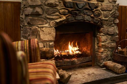 a stone fireplace with a fire in it at Stage House Bed & Breakfast in Glenfinnan