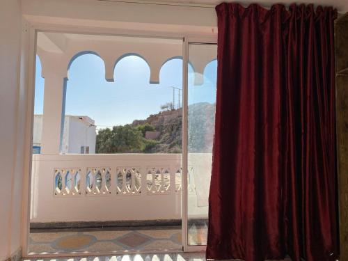 a room with a window with a red curtain at room in tamraght - 10min walk to the beach in Aourir