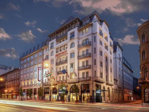 a large white building on a city street at night at Mövenpick Hotel Budapest Centre in Budapest