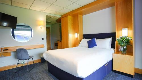 a hotel room with a large bed and a chair at The Bolton Stadium Hotel, a member of Radisson Individuals in Bolton