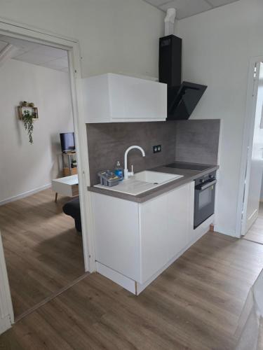 une cuisine blanche avec un évier et une cuisinière dans l'établissement Appartement 6 personnes, vue exceptionnelle sur la montagne, à La Bourboule