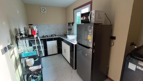 eine Küche mit einem Kühlschrank aus Edelstahl und einer Mikrowelle in der Unterkunft Fern lovely home with big garden in Ko Phangan