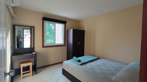 ein Schlafzimmer mit einem Bett, einer Kommode und einem Spiegel in der Unterkunft Fern lovely home with big garden in Ko Phangan