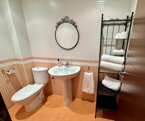 Un baño con inodoro, lavabo y espejo. en Apartamento de lujo en Residencial El Mocan, en Palm-mar