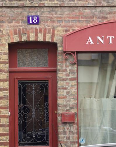 - un bâtiment avec une porte rouge et un panneau au-dessus dans l'établissement La Belle Aventure, à Pont-l'Évêque