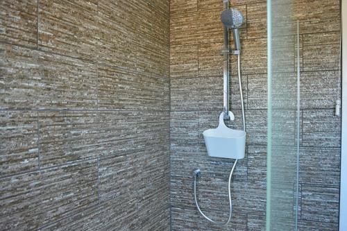 a shower with a bucket in a brick wall at Carreg Coetan Cottage Newport, Pembrokeshire in Newport Pembrokeshire
