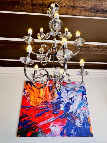 a chandelier hanging from a ceiling with a painting at Vibrant Downtown Studio Oasis in Liepāja