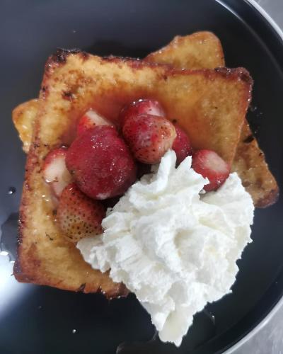 a plate of waffles with strawberries and whipped cream at Hôtel de la Palmeraie in Bujumbura