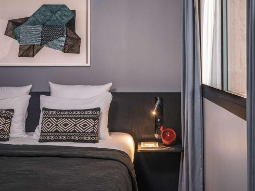 a bedroom with a bed and a nightstand next to a window at Novotel Paris Porte Versailles in Paris