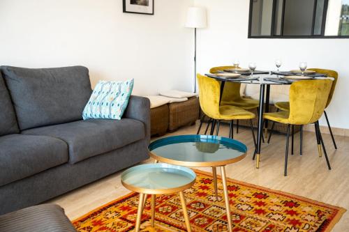 un salon avec un canapé, une table et des chaises dans l'établissement Soléna - Appartement Vue Mer Climatisé 2 Chambres, à Cavalaire-sur-Mer