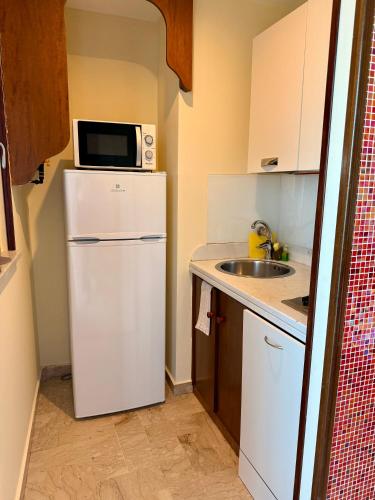 a small kitchen with a white refrigerator and a microwave at MiraMare Residence Cefalú in Cefalù