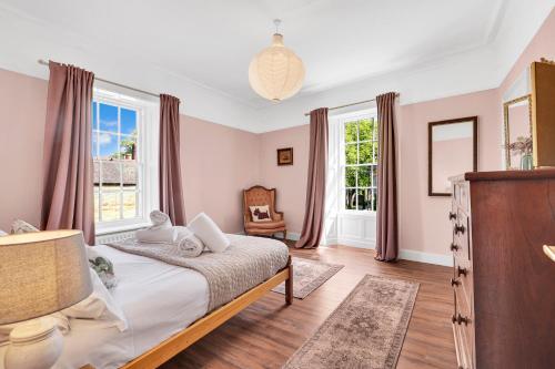 a bedroom with a bed and two windows at Learchild House - North East Escapes in Alnwick
