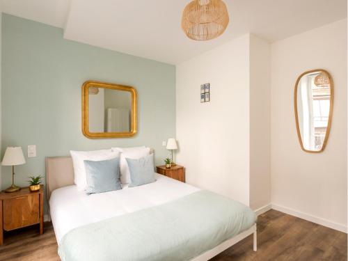 une chambre avec un lit blanc et un miroir dans l'établissement Merveil - Family Suite - Marais - Fbg St Antoine, à Paris