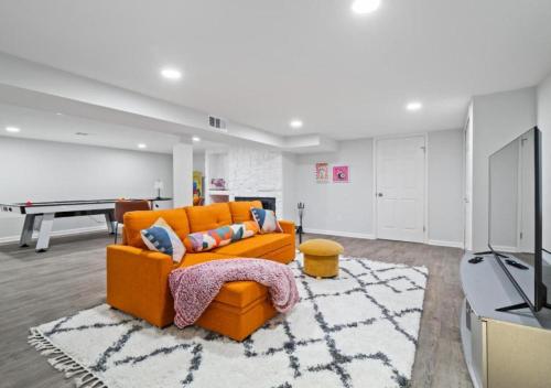an orange couch in a living room with a pool table at Spacious and Luxury Designed Ranch with Game Room in Strongsville