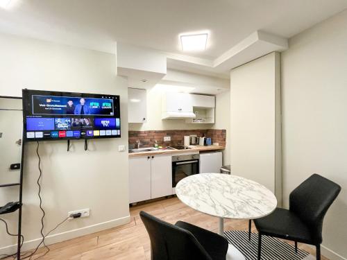 un salon avec une table et une télévision au mur dans l'établissement 162 - Urban Studio in Montorgueil, à Paris
