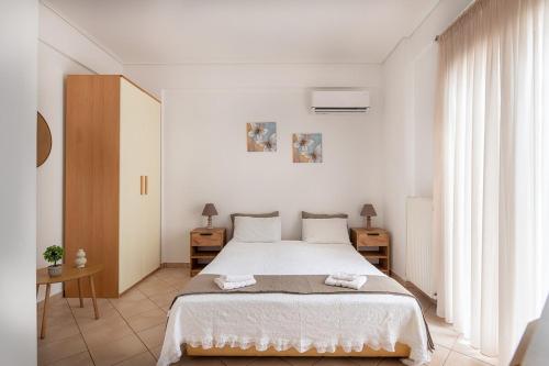 a white bedroom with a large bed and a window at Vista Mare Blu House in Agioi Theodoroi