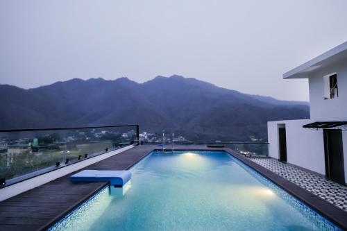 a swimming pool on top of a building with a mountain at ECKO Tapovan by the Ganges in Rishīkesh