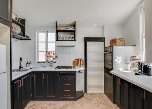 a kitchen with black cabinets and white counter tops at Edwin Cottage in Toowoomba